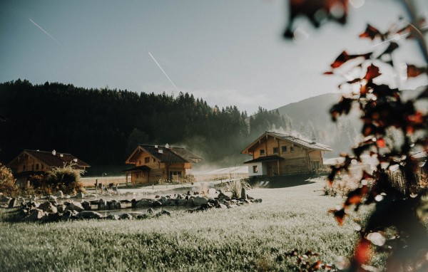 Naturbadeteich in herbstlichem Nebel mit den Chalets im Hintergrund